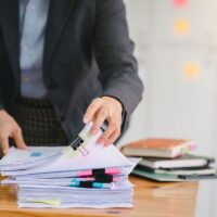 a woman is analyzing reports/claims on a stack of paper