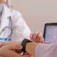 Close-up GP advice AI smart IoT watch guide to patient help collect ECG data, pulse heart rate, blood pressure, wrist sensor sport solution record connect to clinic health device digital platform app.